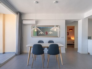 A modern dining area with a white table, two blue chairs, and pendant lights. - Elegant 3BR Apartment in Central Málaga with Terrace, WiFi, and Air Conditioning (Málaga)