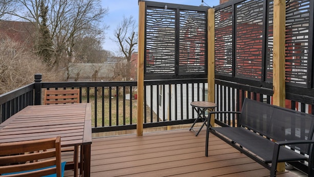 Une terrasse en bois avec une table et des chaises, un banc et une clôture décorative.