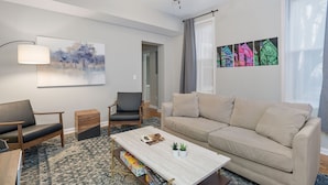 Un salon moderne avec un canapé beige, une table basse, une lampe sur pied et un ventilateur de plafond.