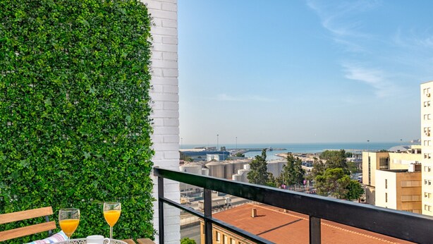 Een balkon met uitzicht op de stad, een tafel met dienblad en twee glazen jus d'orange.