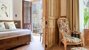 Ein Schlafzimmer mit einem Bett, einem Holzstuhl mit floralem Bezug und einer Holzbank.