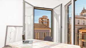 Ein modernes Zimmer mit einem großen Fenster, einem Laptop auf einem Holztisch und einem Stuhl.