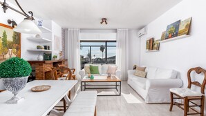 Una sala moderna con un sofá blanco, una mesa de comedor de madera y una chimenea de ladrillo.