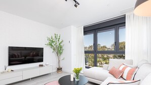 Ein modernes Wohnzimmer mit Flachbildfernseher, einer Couch, einem Couchtisch und einer Topfpflanze.