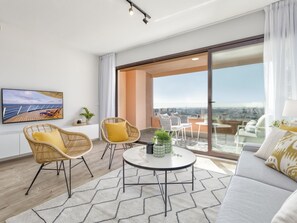 Een moderne woonkamer met een groot raam, een ronde salontafel en comfortabele zitplaatsen.