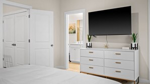 Un dormitorio moderno con una cama grande, un aparador blanco con cajones, un televisor de pantalla plana montado en la pared y una puerta que da a otra habitación.