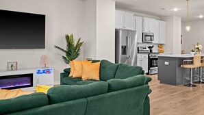 Una sala de estar moderna con un sofá verde, un televisor de pantalla plana y una chimenea.