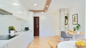 Una cucina moderna con mobili bianchi, un piano di lavoro in legno e una zona pranzo con tavolo e sedie bianche.