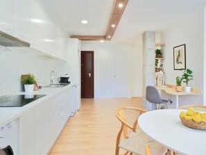 Eine moderne Küche mit weißen Schränken, einer Holzausziehtafel und einem Essbereich mit weißem Tisch und Stühlen.