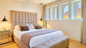 Une chambre avec un grand lit, deux tables de chevet, une commode et une fenêtre avec des rideaux.