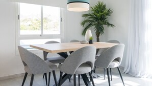 A modern dining area with a wooden table and grey upholstered chairs, a hanging pendant light, and a potted plant. - Top-Floor Apartment Elegance in Carihuela, Torremolinos with Pool and Terrace (Torremolinos)