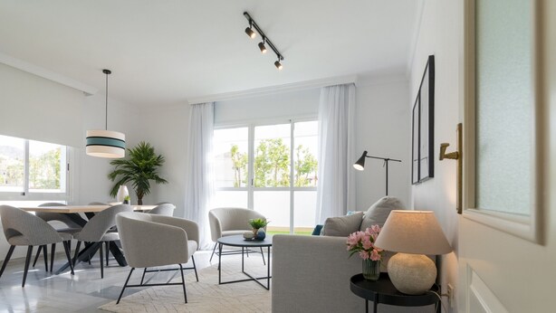 A modern living room with a dining area, large windows, and a view of greenery outside. - Top-Floor Apartment Elegance in Carihuela, Torremolinos with Pool and Terrace (Torremolinos)