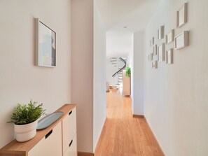 A hallway with a wooden floor, white walls, and a staircase in the distance. - Charming Historic Center Apt with Panoramic Terrace in Málaga (Málaga)