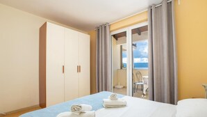 A hotel room with a bed, two towels, a wardrobe, and a balcony with a view. - Apartments Radevenjić (Omis)