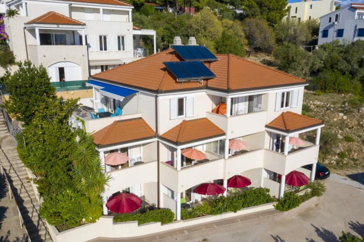 Un edificio residencial de varios pisos con balcones, paneles solares y zonas de estar al aire libre.