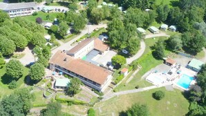 An aerial view of a resort with a central building, multiple cabins, and a swimming pool. - Mobile home with terrace - 4 guests (Saint-Girons)