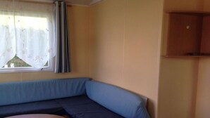 Een kamer met een blauwe bank, een klein rond tafeltje en een raam met gordijnen.