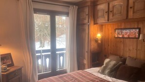 A bedroom with a plaid bedspread, wooden paneling, a window with curtains, and a wall-mounted lamp. - 3-room apartment for 6 people in Combloux (Combloux)