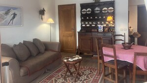 A cozy living room with a sofa, a small table, a patterned rug, and a wooden cabinet with dishes. - 3-room apartment for 6 people in Combloux (Combloux)