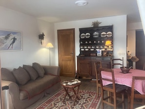 A cozy living room with a sofa, a small table, a patterned rug, and a wooden cabinet with dishes. - 3-room apartment for 6 people in Combloux (Combloux)