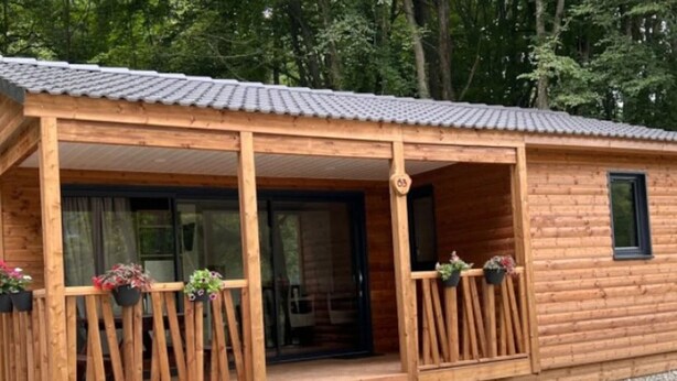 Une cabane en bois dotée d’un porche abrité et d’une petite entrée.