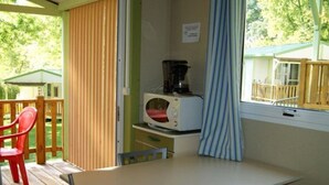 Une petite cuisine équipée d’une table et de chaises, d’un four à micro-ondes et d’une fenêtre avec des rideaux.