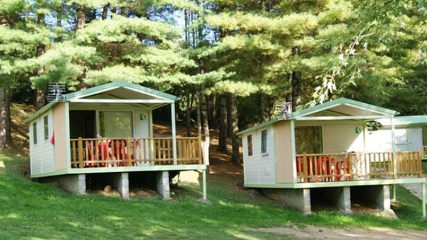 Deux petits chalets dotés de balcons, entourés d’arbres.