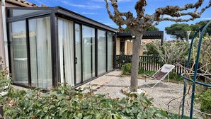 Une maison moderne avec de grandes portes vitrées, un petit jardin et un arbre.