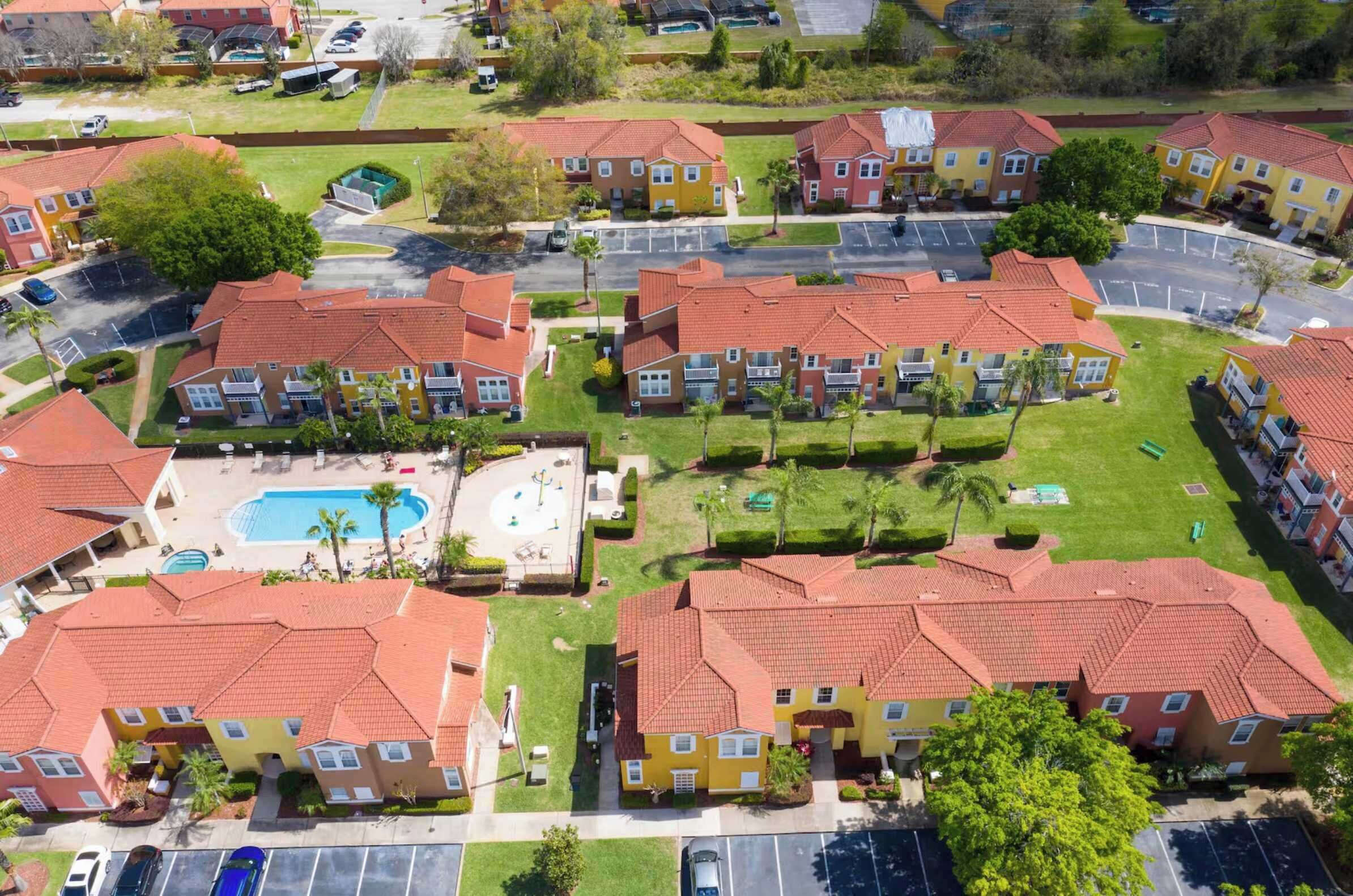 A residential complex with multiple apartment buildings, a central courtyard with a swimming pool, and a parking area.