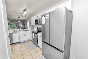 A modern kitchen with stainless steel appliances, white cabinetry, and a tiled floor. - Family Friendly 3BR Home, Quiet, Near Hospitals, Ideal for Travel Nurses (Lakeland)