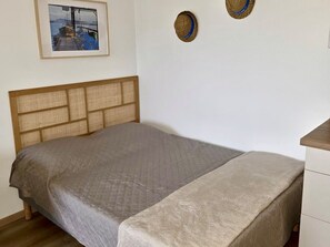 Une chambre à coucher avec un lit, une tête de lit, une table de chevet et un tableau encadré au mur.