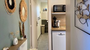 Een keuken met een magnetron, koffiezetapparaat en vaatwasser. Op het aanrecht staan decoratieve wandversieringen en een kleine plant.