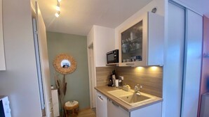 Een kleine keuken met een magnetron, spoelbak en een houten aanrecht.