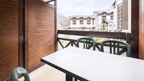 Varanda com piso de madeira, uma mesa e cadeiras.