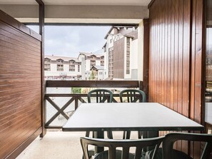 Un balcón con baranda de madera, una mesa y cuatro sillas.
