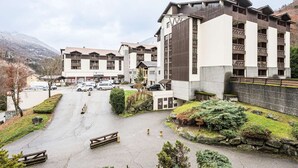 Hotel com vários andares, estacionamento e montanhas ao fundo.