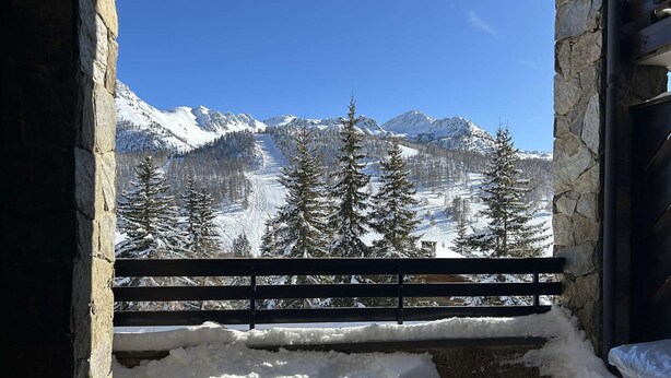 A stone-framed window with a wooden bench, overlooking a snowy mountain landscape with evergreen trees. - Cozy Apartment for 4 with Balcony and Parking in Montgenèvre (Montgenèvre)