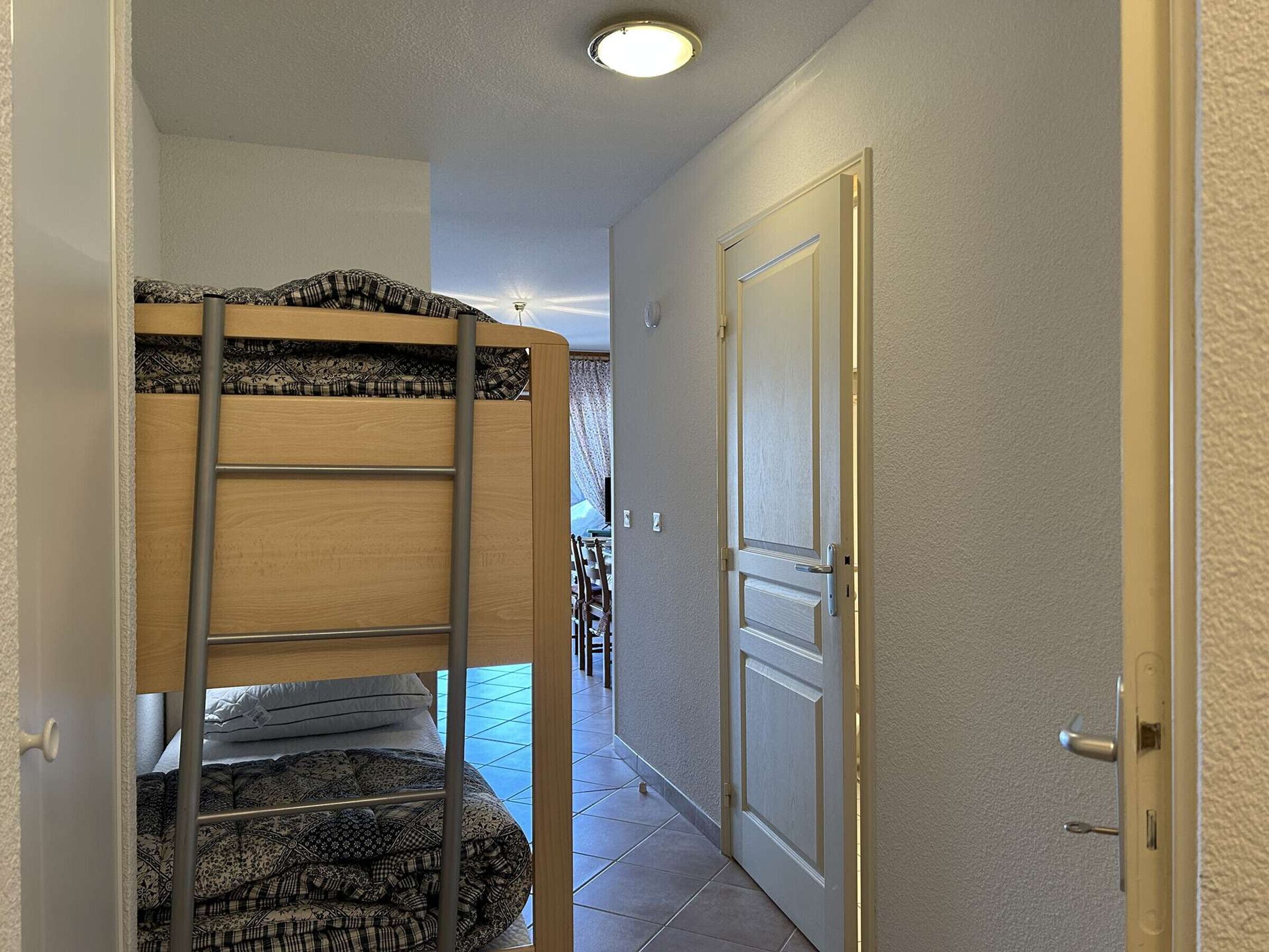 A narrow hallway with a bunk bed on the left and a closed door on the right.