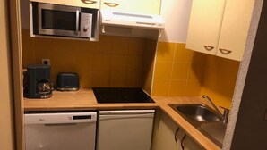 Une cuisine compacte équipée d’un four à micro-ondes, d’un grille-pain et d’un lave-vaisselle.