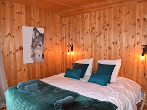 A wooden-paneled room with a bed, pillows, and a wall-mounted light fixture. - Cozy Chalet in Montgenèvre with WIFI and Fireplace (Montgenèvre)