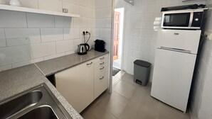 A modern kitchen with white cabinets, a stainless steel sink, a kettle, a coffee maker, a microwave, and a refrigerator. - Spacious apartment 5 min from beach, 2 bedrooms, terrace, parking, WIFI (Roses)