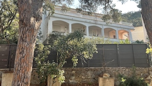 A white building with multiple arches and a stone wall in front. - Spacious apartment 5 min from beach, 2 bedrooms, terrace, parking, WIFI (Roses)
