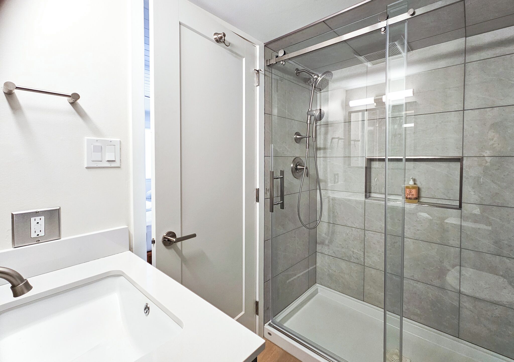 Une salle de bain moderne avec une douche à parois de verre, un lavabo blanc et un porte-serviettes.