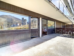 A building with a covered outdoor area, large windows, and a view of a mountainous landscape. - Bright Apartment · Ski-in/Ski-out · Terrace & Ski Locker (Les Menuires)