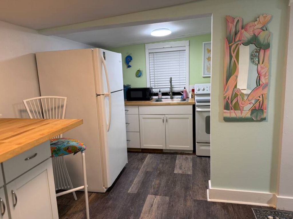 A compact kitchen with a refrigerator, microwave, stove, and sink.