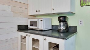 Cozinha com armários brancos, micro-ondas e cafeteira em bancada preta.