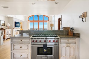 A kitchen with a large island, a built-in oven, and a view of the sea through a large window. - Beachfront with 4 Beds and Baths! | Sea La Vie (Folly Beach)