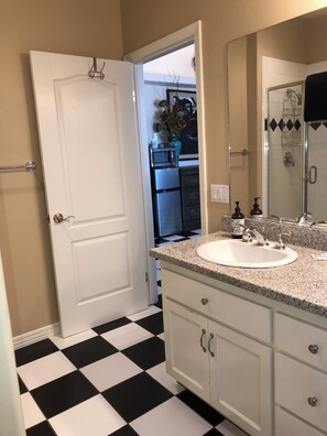 Un baño con un lavabo blanco, un espejo y una ducha.