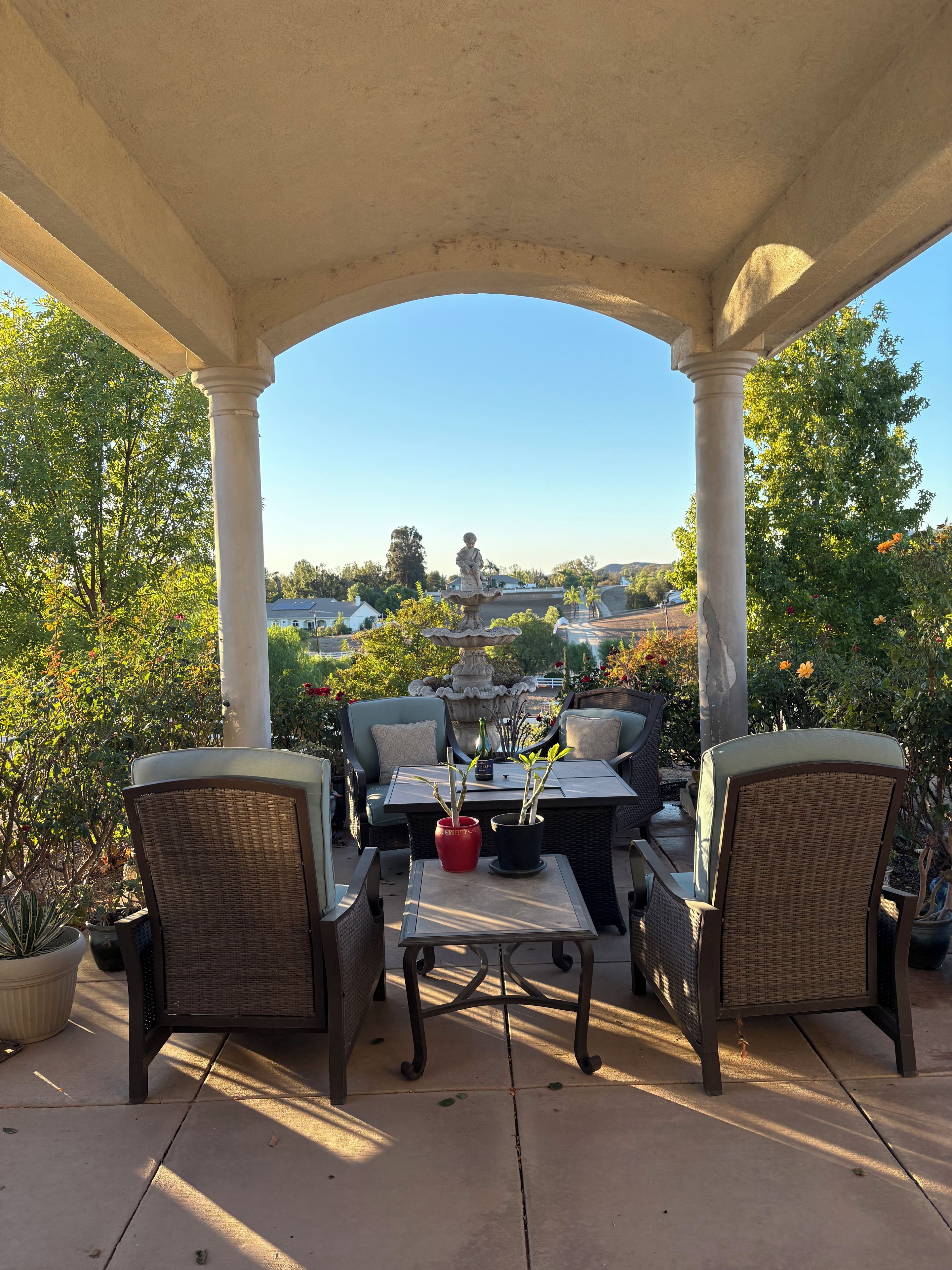 An outdoor patio with a covered seating area, a table with chairs, and a view of a residential area.