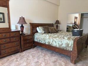 Un dormitorio con una cama de madera, dos mesitas de noche con lámparas, un aparador y un espejo.